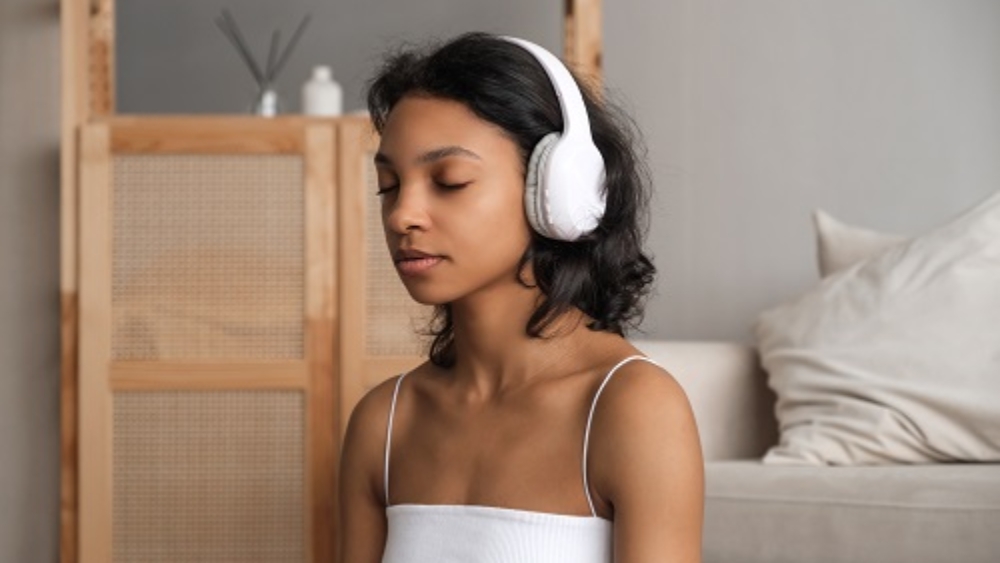 Wellbeing and wellness concept banner with relaxed young woman meditating in headphones