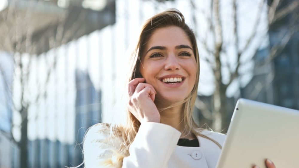 photo of a woman holding a notepad and smiling while talking on the phone