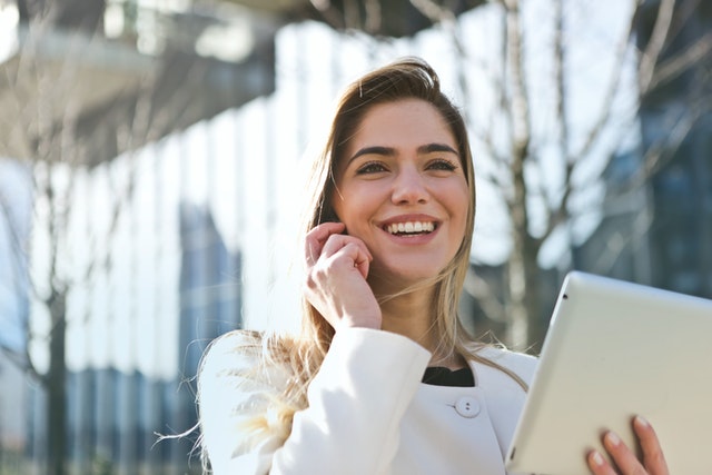 photo of a woman holding a notepad and smiling while talking on the phone