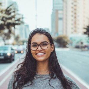 woman of color smiling at camera near a busy city street